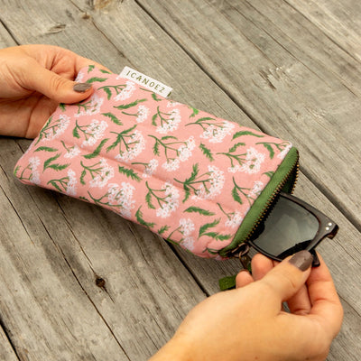 Floral-patterned pouch with sunglasses on a wooden surface